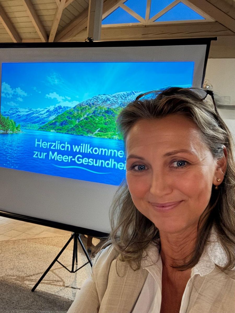 Irene Bux vor der Leinwand mit der Begrüßung „Herzlich willkommen zur Meer-Gesundheit“